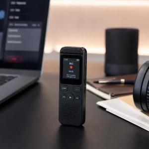 Mini registratore vocale digitale su scrivania con cuffie e laptop in ambiente moderno